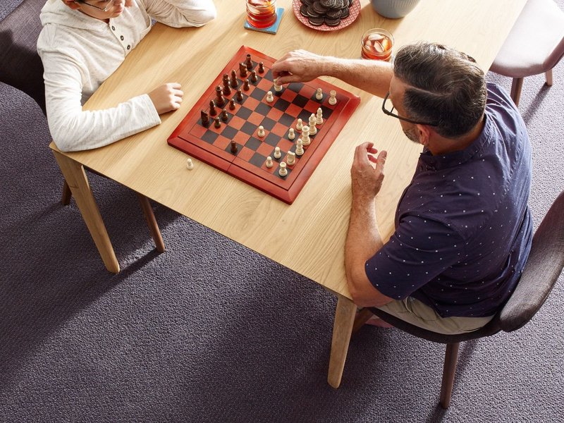 child and father playing chess on table