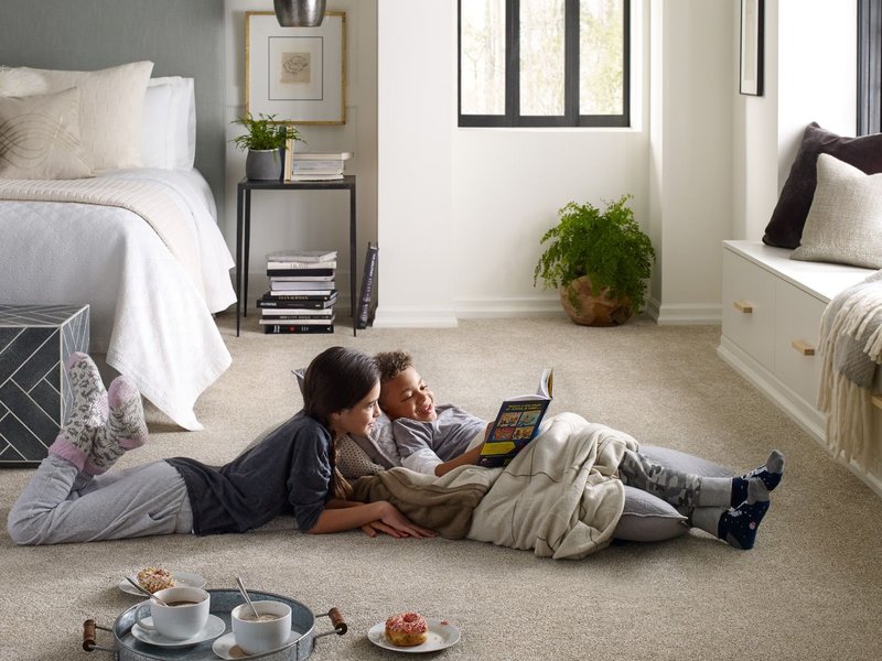 kids laying on carpet in bedroom reading a book