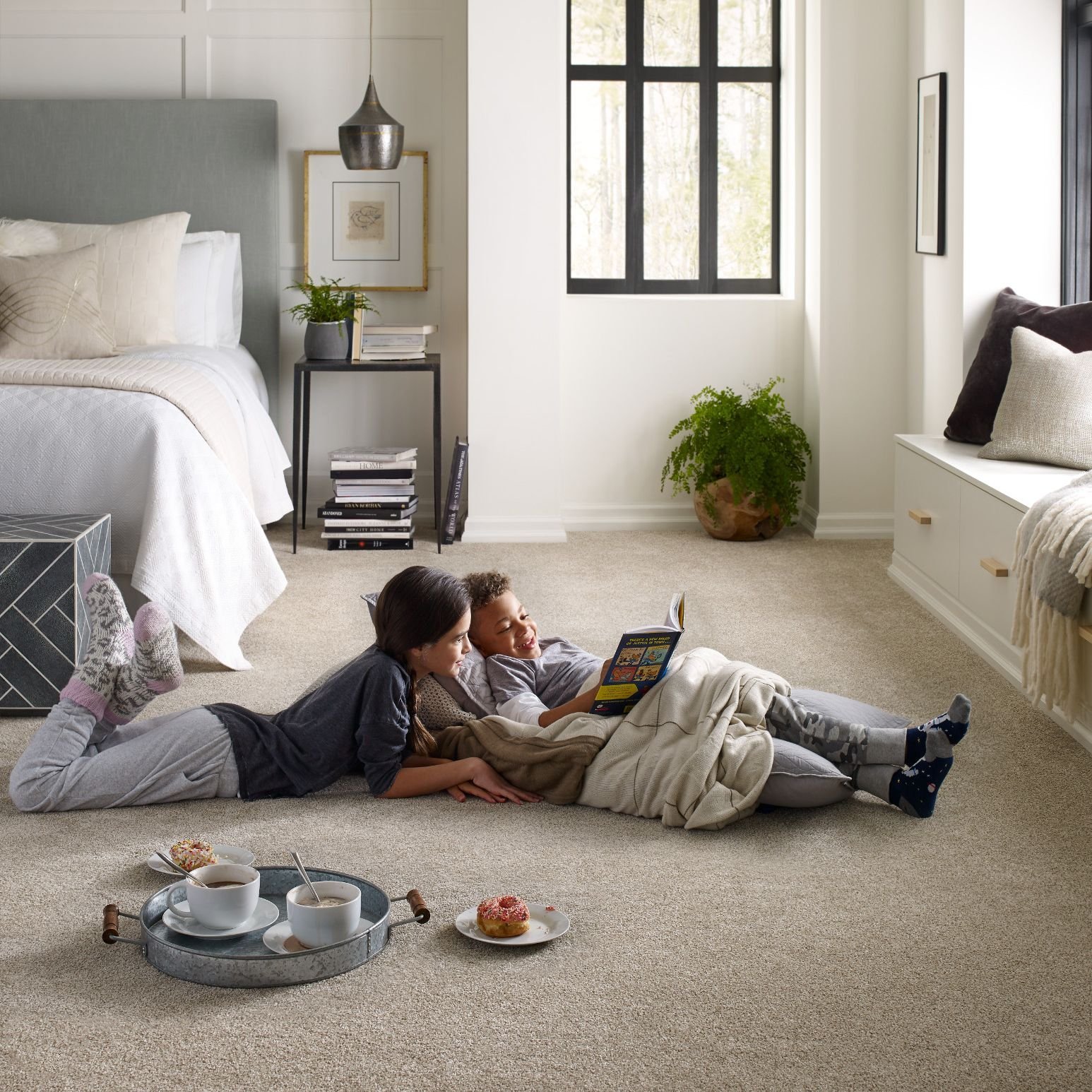 kids laying on carpet in bedroom reading a book