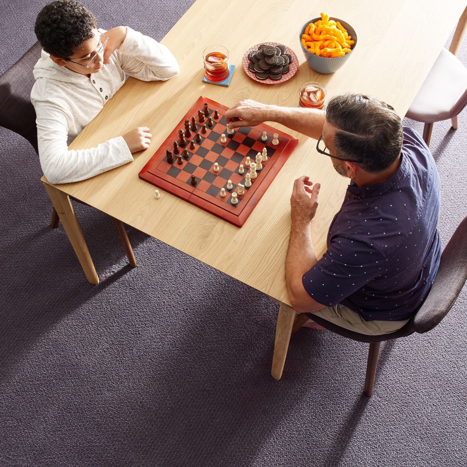 child and father playing chess on table